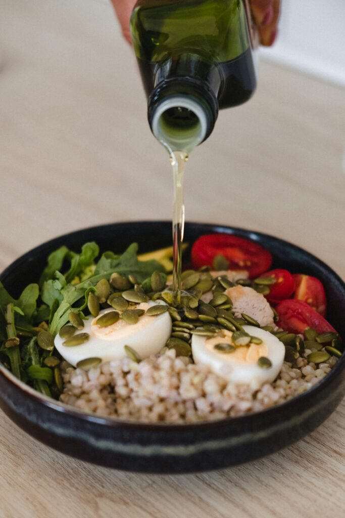 Delicious whole grain salad with fresh vegetables, pumpkin seeds, and olive oil pour.